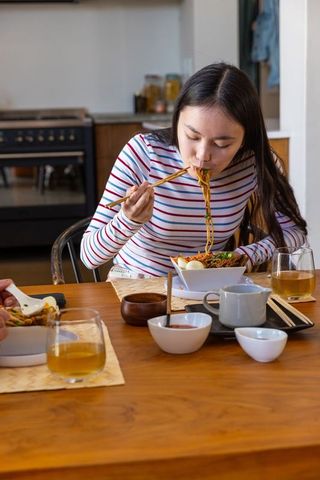 Friends sharing noodle meal at rustic kitchen table