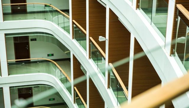 Curved glass balconies in modern multi-level office atrium with warm wood handrails