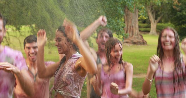 A group of diverse young adults is joyfully dancing in the rain in a park, with copy space. Their cheerful expressions and soaked clothes suggest a spontaneous and carefree moment of fun.