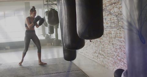 Female boxer training barefoot in urban gym
