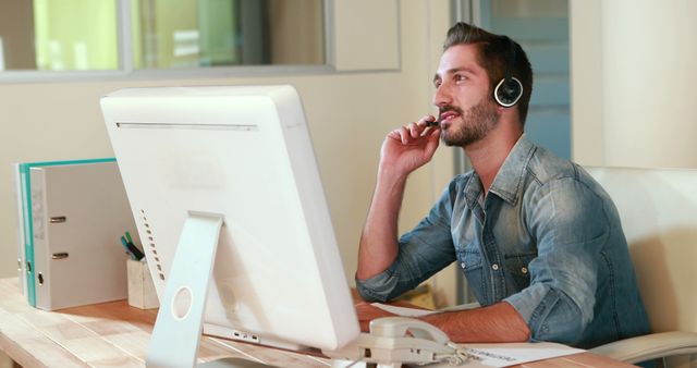 Customer support representative working at desk in modern office, wearing headset. Ideal for use in business, customer service solution visuals, tech support concepts, and professional workplace environment illustrations.