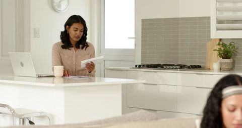 Joyful Mother and Daughter Bonding Over Letter in Modern Kitchen
