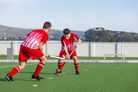 Teammates Playing Field Hockey on Turf
