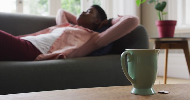 Relaxed Young Adult Resting on Sofa with Cup of Tea in Living Room - Download Free Stock Images Pikwizard.com