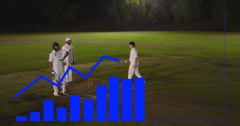 Night cricket under floodlights with bowler approaching crease and batsmen standing, blue overlay