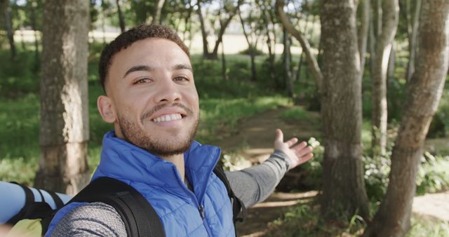 Young man enjoys outdoor adventure by taking a selfie while hiking in forest. Perfect for outdoor activity promotions, travel blogs, nature exploration websites, and advertisements focusing on adventures, healthy lifestyle or eco-tourism.