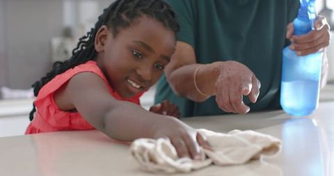 Senior woman guiding child cleaning kitchen counter together multigenerational teamwork