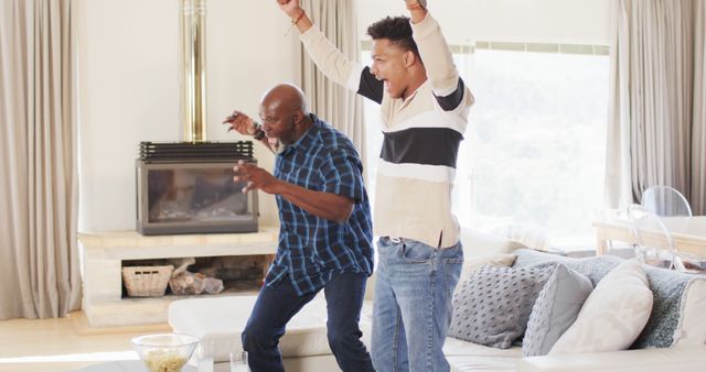 Excited african american father and adult son watching sport on tv and celebrating - Download Free Stock Photos Pikwizard.com