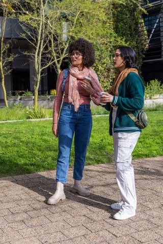 Multicultural students chatting with coffee and smartphone on campus, student lifestyle