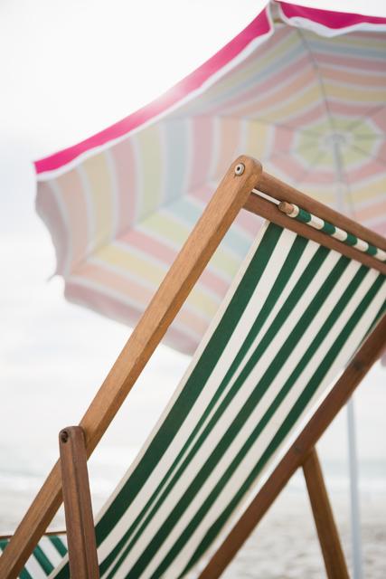Low angle view of empty beach chair and parasol