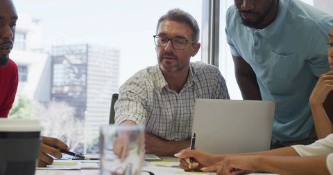 Team Leader Pointing During Strategy Meeting in Modern Office With Laptop and Documents