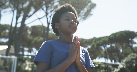 African american teen praying in sunny park, mindfulness, meditation and solitude