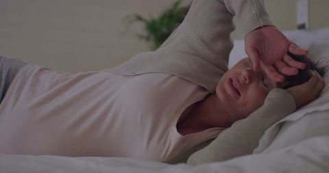 Pregnant woman resting on bed feeling tired with wearable breath tracker overlay