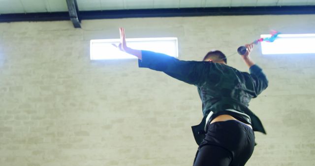 Rear View of Person Practicing Martial Arts with Weapon in Warehouse - Download Free Stock Images Pikwizard.com