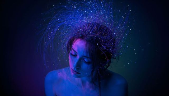 Model tilting fiber-optic halo eyes closed ethereal neon portrait luminescent strands