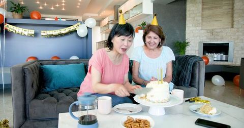 Senior Women Celebrating Birthday with Cake in Cozy Living Room