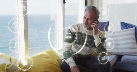 Man conversing on smartphone in ocean-view lounge with digital interface