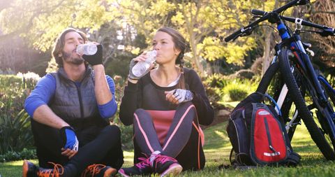 Cyclists Resting and Hydrating in Lush Park Setting