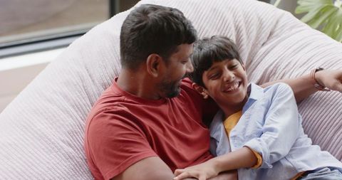 Father and Son Laughing Together on Beanbag Lounge