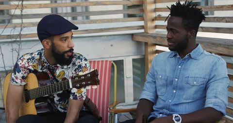Friends Enjoying Rooftop Music Discussion, Guitar in Hand