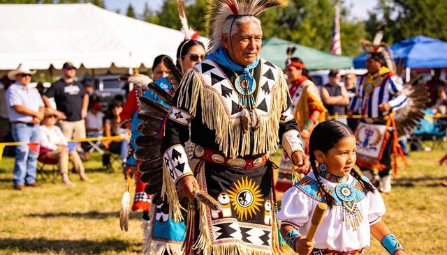 Elder and young girl dancing in buckskin regalia at vibrant powwow celebration