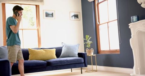 Man Talking on Smartphone Pacing in Comfortable Living Room