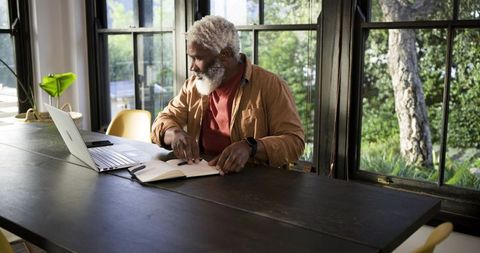 Senior African American Man Working from Rustic Home Office with Laptop