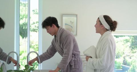 Asian man and african american woman enjoying morning routine at bright bathroom vanity