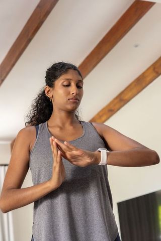 African american woman checking smartwatch during home meditation and mindfulness practice