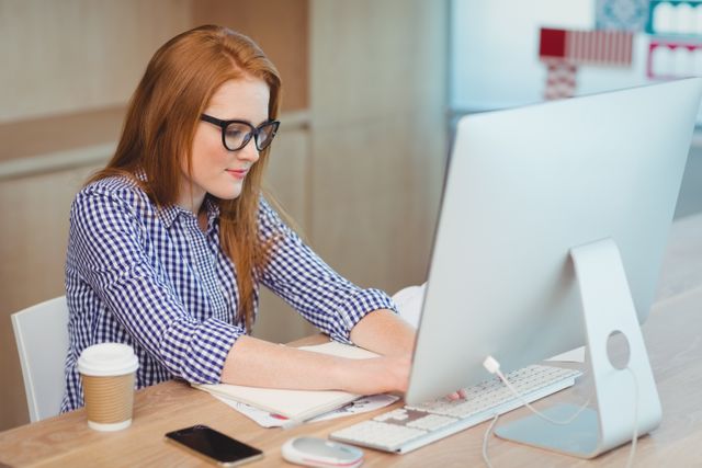 Female executive working on computer in modern office. Ideal for business, technology, and professional workplace themes. Useful for illustrating corporate environments, productivity, and office settings.