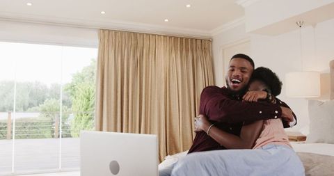 Joyful Couple Laughing Together on Laptop at Home
