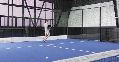 Man on blue padel court with racket and net