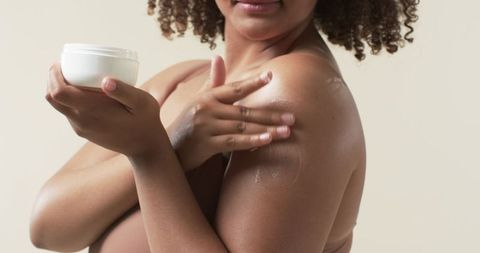 Confident plus size woman embracing self-care with moisturizer