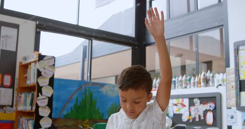 Asian schoolboy raising hand in classroom engaged in learning activity