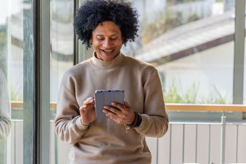 African american man smiling while using tablet in modern coworking space for remote work