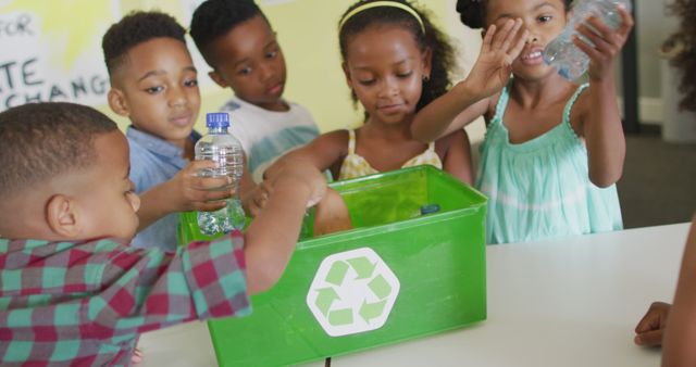 Children enthusiastically recycling plastic bottles in a classroom setting. This stock photo is ideal for use in educational materials, eco-friendly campaigns, school programs that promote recycling and sustainability, environmental awareness blogs, or social media content advocating for responsible waste management.