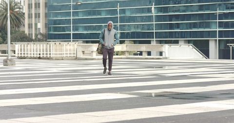 African American Man Walking Across Striped Urban Plaza Carrying Duffel Bag Under Overcast