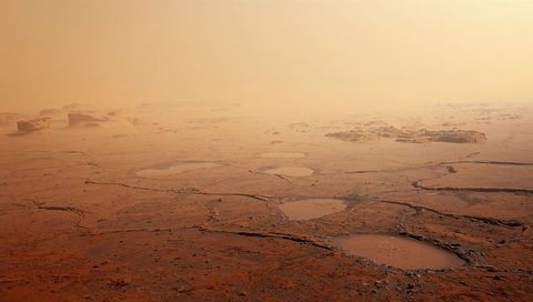 Cracked Arid Plain with Shallow Salt Pans and Mesa Outcrops under Hazy Orange Sky