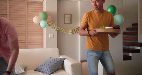 Man Arranging Birthday Snacks in Festive Living Room