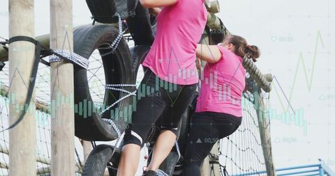 Women climbing tire obstacle on outdoor ropes course