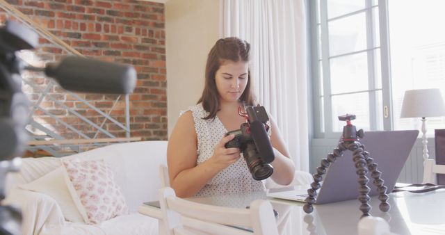 Female photographer is sitting at home studio reviewing camera settings. Useful for articles about female photographers, technology in modern photography, and home studio workspaces.