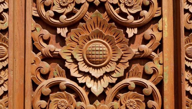 Ornate carved wooden panel with central floral rosette, scrollwork patina and relief detail