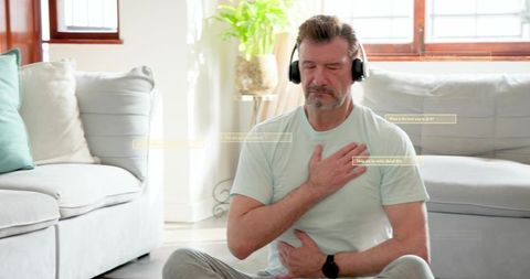 Mature man practicing guided breathwork with headphones in sunlit minimalist living room