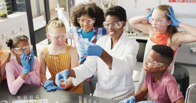 Children of different ethnicities engaging in a fun scientific experiment in a lab under the guidance of a teacher. They wear safety goggles and gloves. Perfect for educational marketing materials, school brochures, or publications promoting STEM education.