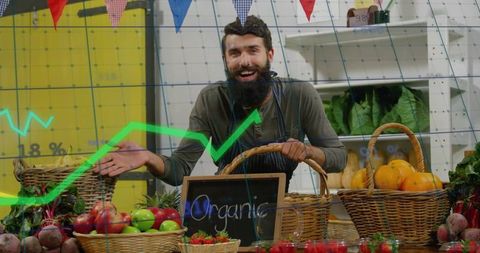 Bearded market vendor arranging organic fruit baskets and smiling behind chalkboard sign