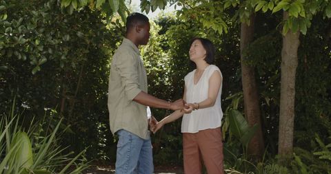 Joyful Couple Holding Hands in Lush Garden Atmosphere