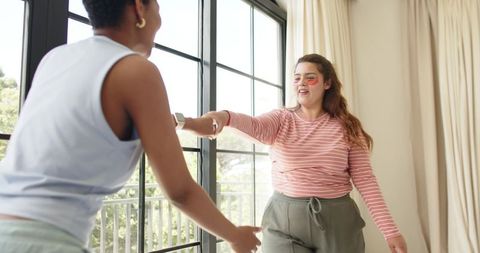 Friends enjoying morning skincare routine on sunlit balcony with under-eye patches