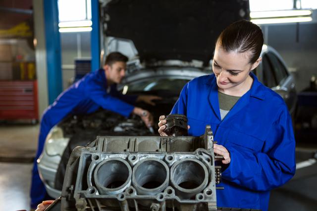 Female mechanic working on engine at repair garage
