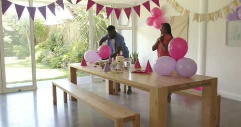 Couple decorating for party celebration with balloons and hats