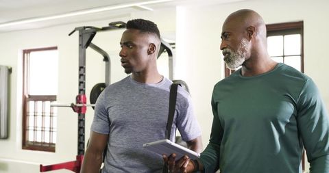 Athletic Men Analyzing Fitness Data in Modern Gym